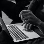 Black and white photo: Student works with laptop in lap