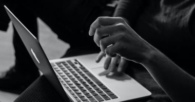 Black and white photo: Student works with laptop in lap